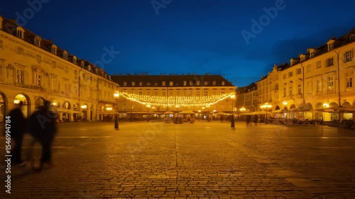 People Walking Through City Square at Dusk with Decorative Lighting