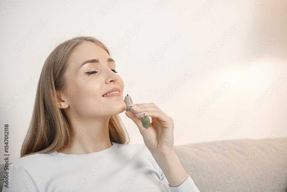 Portrait of woman sitting in living room holding a face massager Portrait of woman sitting in living room holding a face massager