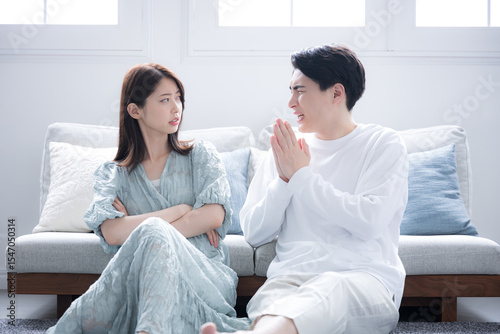 カップルで喧嘩をして謝る男性と女性　ごめんなさいと謝る全身