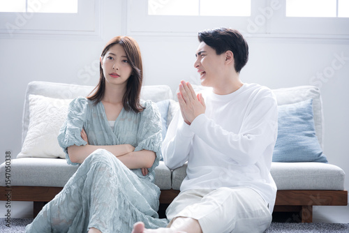 カップルで喧嘩をして謝る男性と女性　ごめんなさいと謝る全身