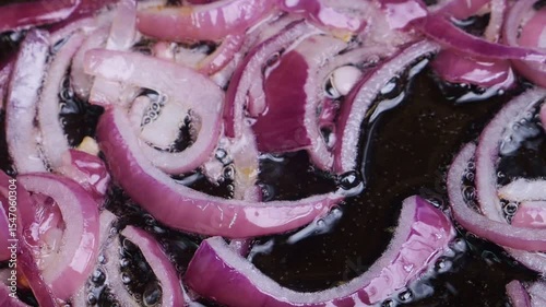 Red sliced ​​onion is fried in vegetable oil hot frying pan. Medium shot.