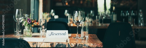 Φωτογραφία Cozy restaurant table with 'Reserved' sign, elegant glassware, and floral centerpiece