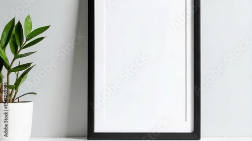 Wallpaper Mural Black rectangular picture frame with white matte on light gray background next to a potted green plant sitting on a white surface. Torontodigital.ca