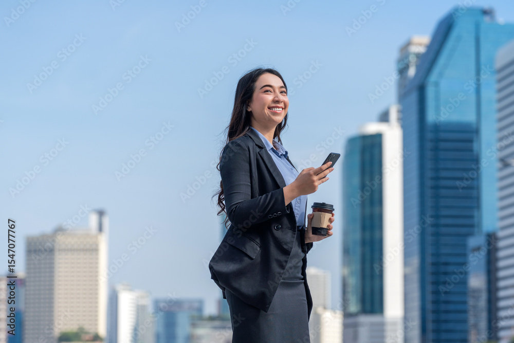 Asian businesswoman using phone in central business district. Businesswoman holding coffee and using smartphone outdoors with modern cityscape background. Asian businesswoman using phone in central business district. Businesswoman holding coffee and using smartphone outdoors with modern cityscape background.