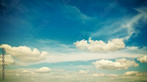 Time lapse of fluffy white clouds drifting across a vivid blue sky on a sunny day, creating a serene and peaceful atmosphere.