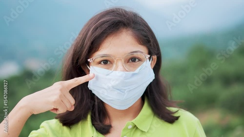 4K portrait of Indian girl wearing mask and giving thumbs up. Background for healthcare, wellness and bacteria safety support. Face mask to stay safe from corona virus covid-19 flu.