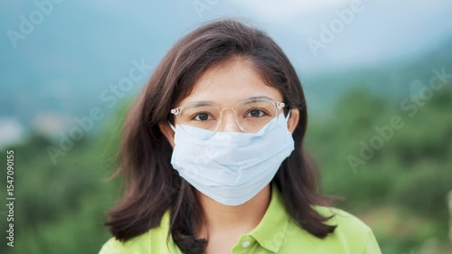 4K Portrait of young Indian woman wearing mask and giving thumbs up. Female tourist wearing mask to protect herself from flue, corona virus and pollution. Health care and safety concept