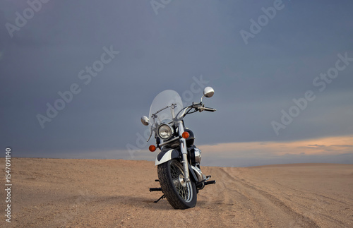 Off-road motorcycle standing still in the open desert beneath heavy clouds. A strong visual of freedom, rugged adventure, and the thrill of riding through wild, untamed terrain.