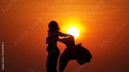 Silhouette shot of carefree Indian girl twirl and enjoy warm sunrise. Travel blogger enjoying holidays. Travel and holidays concept.