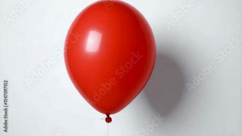 Bright red balloon floating, isolated on a plain white background with subtle shadows adding depth and dimension.