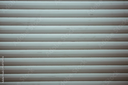 Closed metal roller shutter door is showing muted greenish-gray horizontal slats in flat design