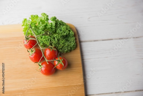 Tomatoes and parsley on chopping board over wooden floor