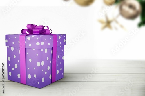 Flat design purple polka-dot gift box is sitting on tabletop with magenta bow, starfish and foliage