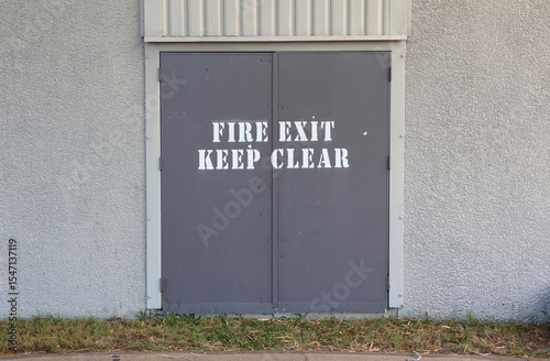 Fire Exit Keep Clear sign painted on grey gray double doors of a building