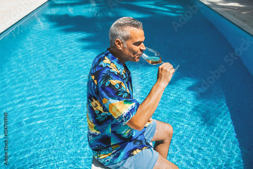 Tourist drinking rose wine by the poolside on a sunny day
