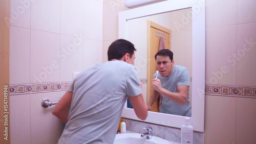 Enthusiastic man singing with toothbrush in bathroom mirror