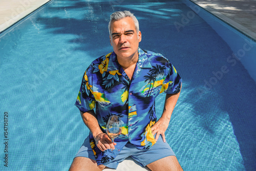 Mature man relaxing in swimming pool with rose wine