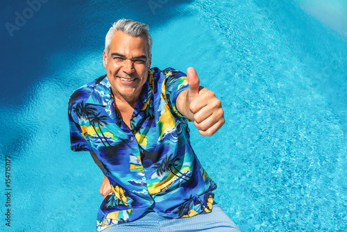 Happy mature tourist giving thumbs up by the poolside