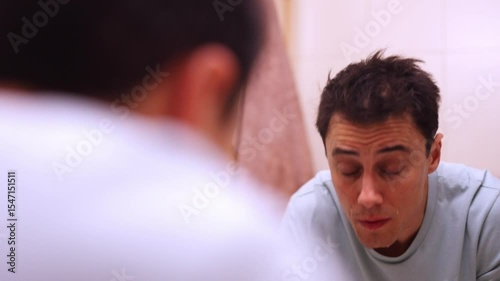Sleepy man washing face in bathroom sink