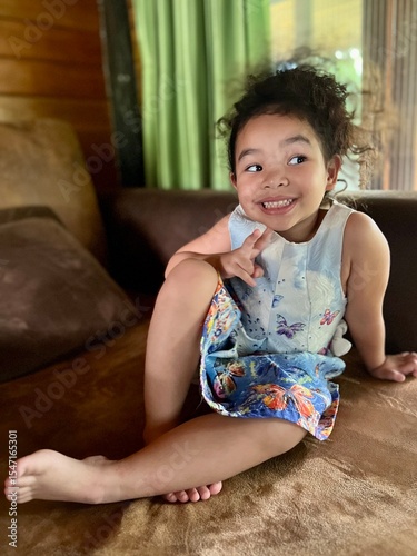 Portrait of a cute little girl sitting on the sofa at home