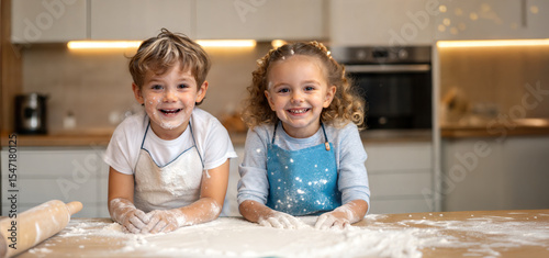 Two smiling children covered in flour while baking in the kitchen, with aprons on. This heartwarming scene captures the joy of culinary exploration and childhood fun