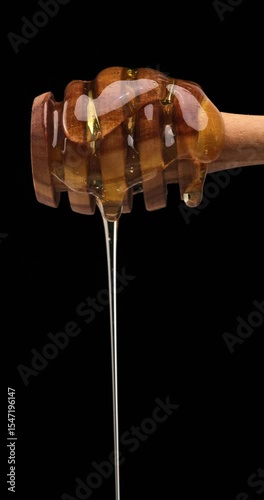 smooth cascade of real honey from dipper to air, captured mid-drip, reveals the luxurious texture and natural beauty of honey