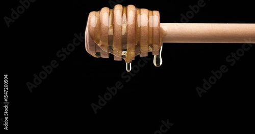 horizontal video of shiny golden real honey dripping of honey spoon in slow motion, highlighting its silky texture and natural shine