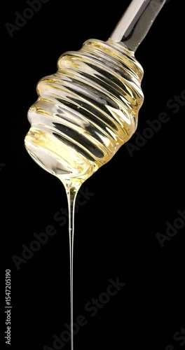 thick golden honey sliding smoothly off the dipper, showcasing its natural amber colour and irresistible viscosity