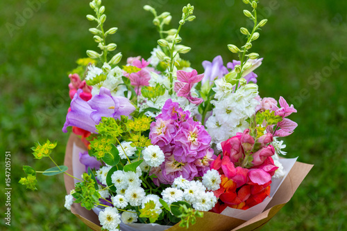 Wrapped flower bouquet made of mixed spring flowers. Beautiful pastel colored fresh flowers arrangement. Birthday bouquet with snapdragons, matthiola and canterbury bells.