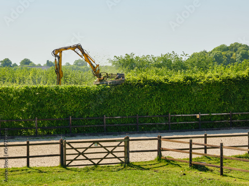 Canvastavla Hidden Hedge trimming machine cutting hughe orchard hedges, with fruit trees in the background in Zuid-Beveland, Zeeland, Netherlands