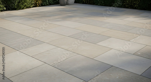 A close up view of a stone patio with a few plants and two pots in the background on a sunny day