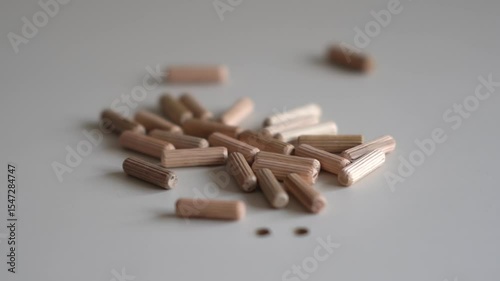 Wooden furniture pegs scattered on the surface of the chipboard. Furniture assembly at home. hand takes wooden pegs for assembling furniture