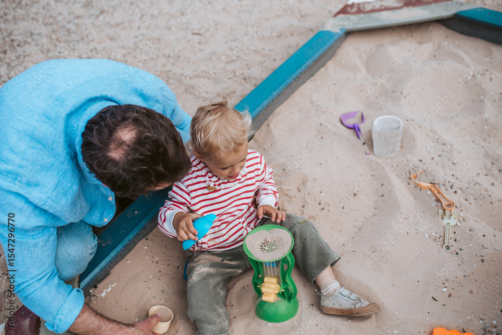 Naklejka premium Top view of dad and son playing in the sandbox on playground.