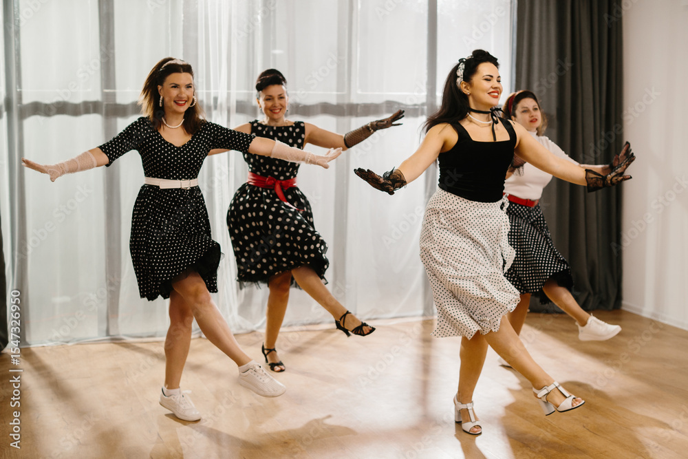 Naklejka premium Four pinup dancers wearing fifties style polka dot dresses and performing rock and roll dance steps