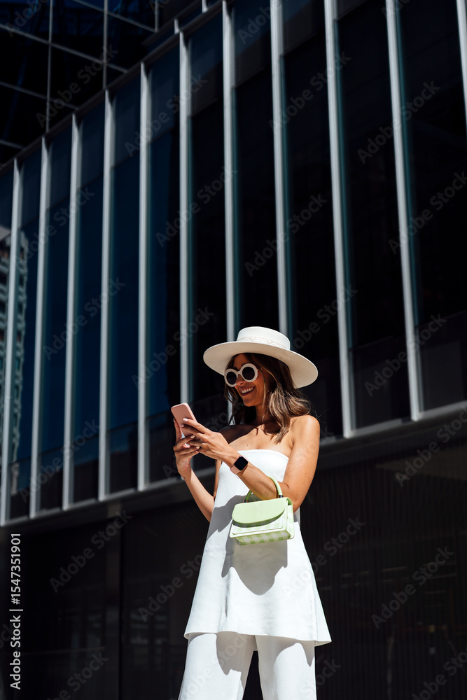© Westend61 - Stylish woman using smart phone outside building on sunny day