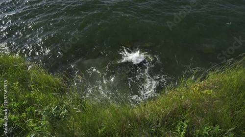 Strong wind on the Baltic coast. Waves break the high bank. Green grass on the shore sways in the strong wind. Paldiski. Estonia, Gulf of Finland. Baltic sea