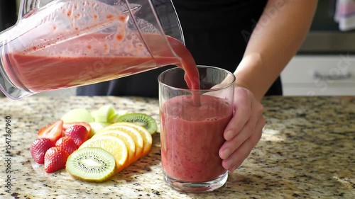 Pouring Pink Smoothie into Glass with Fruit Beside