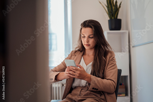 Young businesswoman with long hair using smart phone at home