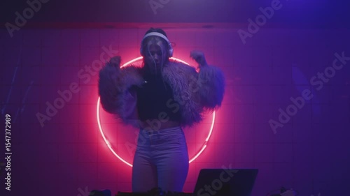 Woman DJ dancing in club, creates electronic music. Beautiful female artist and mixer board