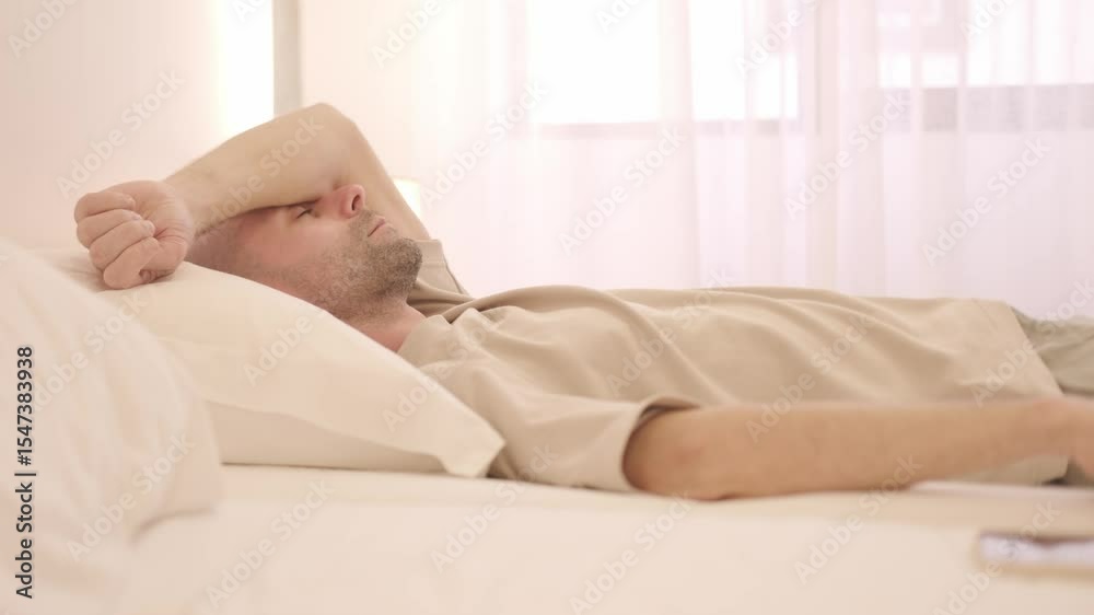 Tired Sleep-deprived young man lies in bed struggles with insomnia, unable to sleep. Sleep disorder, overthinking, restless thoughts deprivation, mental health, sleeping issues, disturbances