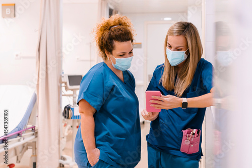 Mature nurse with colleague using smart phone at hospital photo