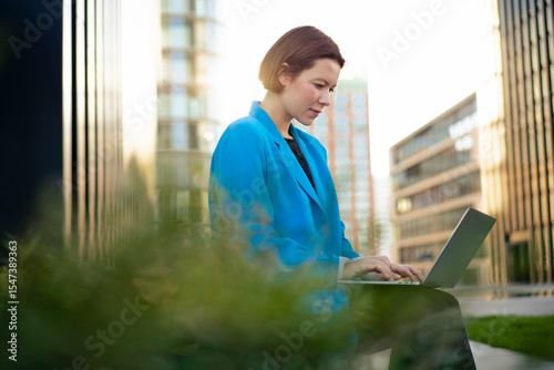 Businesswoman working on laptop sitting by plants
