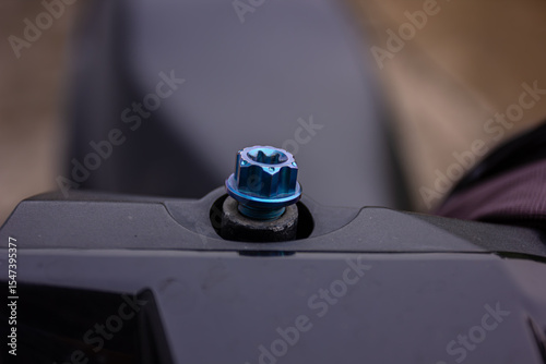 A macro close-up of a blue titanium bolt or nut on a motorcycle or car part. A concept of vehicle tuning and accessories.