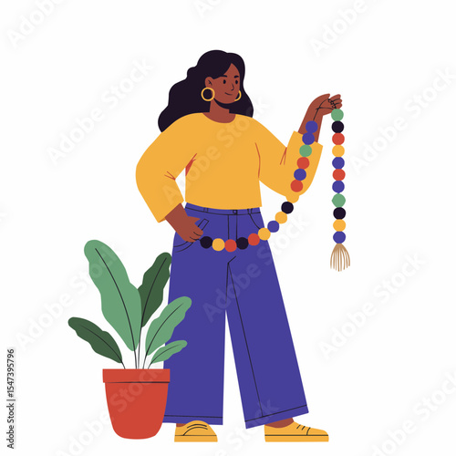Black woman holding colorful wooden bead garland beside plant  