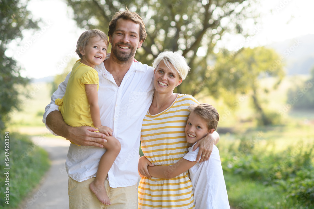 Fototapeta premium A portrait of young family with small children in sunny summer nature.