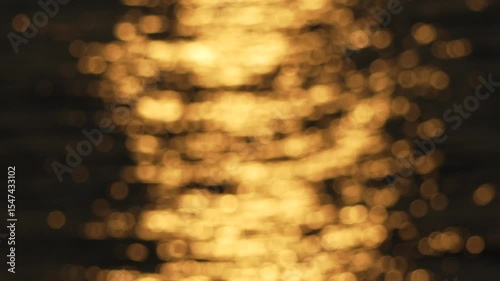 blurry, yellowish-orange sunset over water. The water appears to be rippling and the sky is filled with a warm, golden glow.