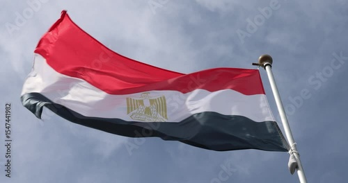 4K video The flag of Egypt is waving against the background of a clear blue sky with white clouds. Close-up, perfect for news.