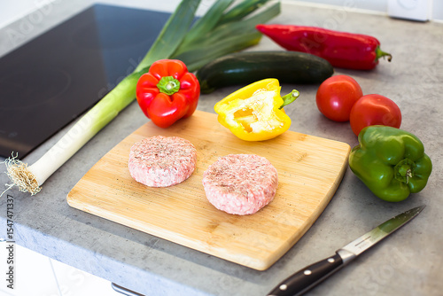  Raw Burger Patties with Fresh Vegetables on Wooden Board