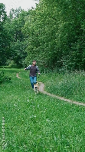 young man in plaid shirt playing training petting hugging and kissing his dog during summer park walk happy loving companionship concept lifestyle	