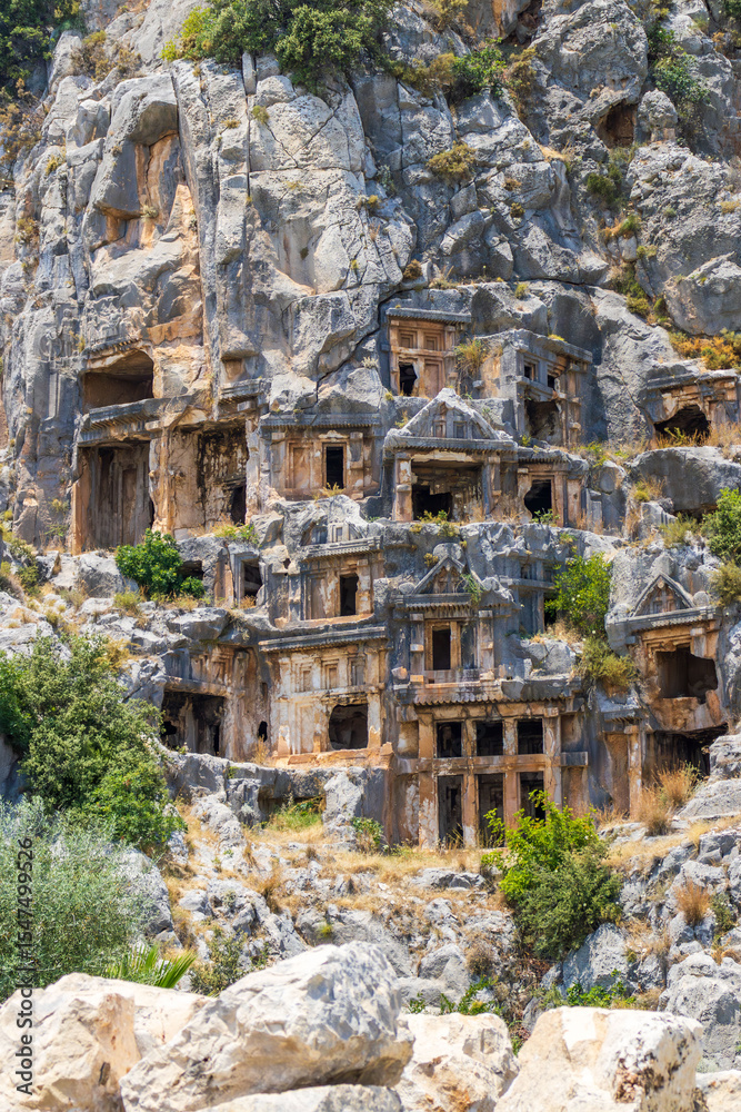 Fototapeta premium Demre, Turkey - June 14, 2025:View of the ancient Lycian necropolis and Roman amphitheater in the ruins of Myra, located in Demre, Antalya Province, Turkey.